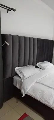 a bed with a gray headboard and pillows on it at Cheers in Evander