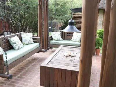 a porch with two swing chairs and a table at Monkey Thorn in Roodeplaat