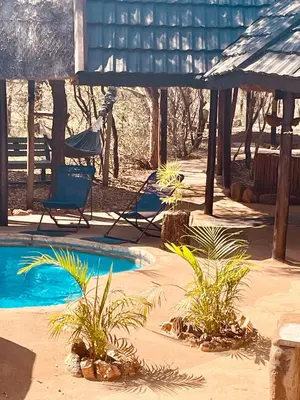 a swimming pool with two chairs and a hammock at Nyala Luxury Safari Tents in Marloth Park