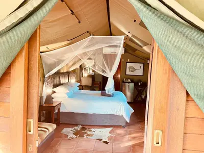 a bedroom with a large bed with a canopy at Nyala Luxury Safari Tents in Marloth Park