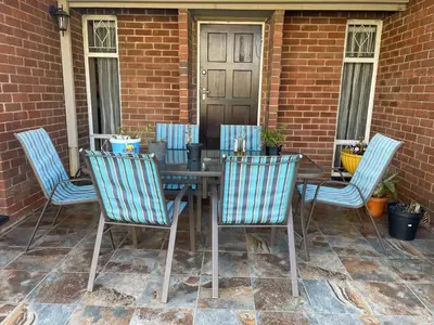 a wooden table with four chairs around it on a patio at Tranquil Haven in Kempton Park