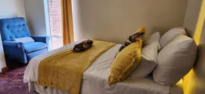 a bedroom with a bed with pillows and a blue chair at Tranquil Haven in Kempton Park