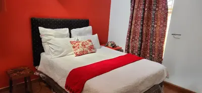 a bedroom with a bed with a red wall at Tranquil Haven in Kempton Park