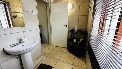 a bathroom with a white sink and a mirror at Aspen Guest House NO LOADSHEDDING in Centurion