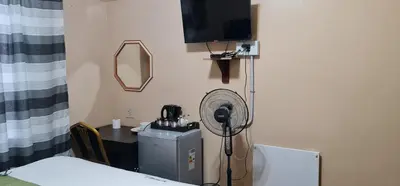 a room with a desk with a fan and a table with a mirror at My House Guest House in Pretoria