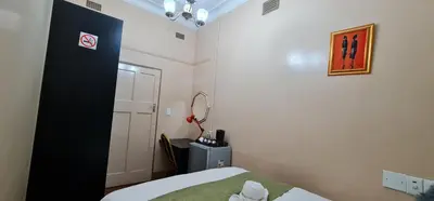 a small room with a bed and a mirror at My House Guest House in Pretoria
