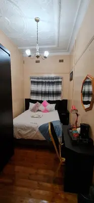 a bedroom with a bed and a table in it at My House Guest House in Pretoria