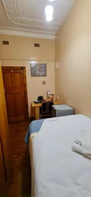 a bedroom with a bed and a desk with a table at My House Guest House in Pretoria