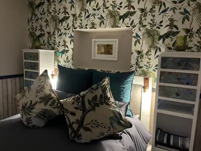 a bedroom with a bed with pillows and floral wallpaper at A Bird Cage Stay & Cottage in Haenertsburg