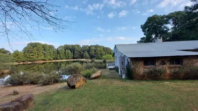 a building in a field next to a lake at Lake House in Dullstroom
