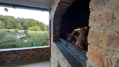 a brick wall with a window with a view of a field at Lake House in Dullstroom