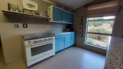 a kitchen with a stove and blue cabinets and a window at Lake House in Dullstroom