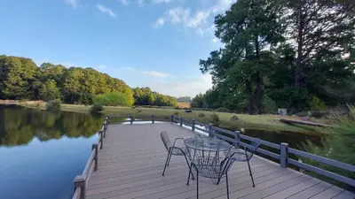 a table and chairs on a wooden boardwalk next to a river at Lake House in Dullstroom