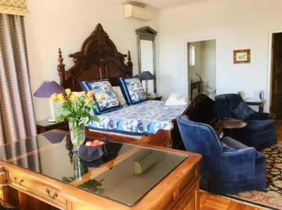 a bedroom with a bed and two blue chairs at Waterkloof Mansion Boutique Hotel in Pretoria