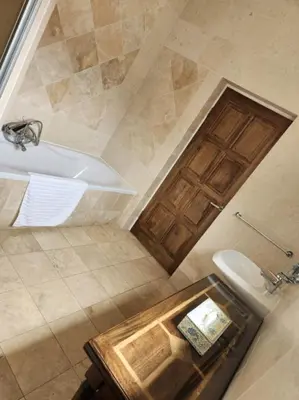 a bathroom with a tub and a toilet and a wooden door at Waterkloof Mansion Boutique Hotel in Pretoria