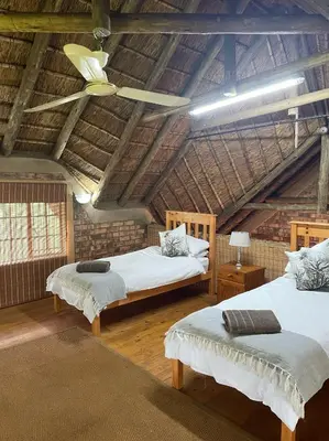 a attic bedroom with two beds and a ceiling at Intundla's Rest in Marloth Park