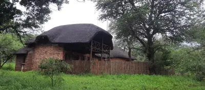 an old brick barn with a thatched roof in a field at Intundla's Rest in Marloth Park