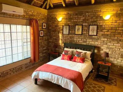 a bedroom with a bed and a brick wall at Intundla's Rest in Marloth Park