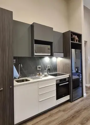 a kitchen with white cabinets and a sink and a microwave at Top Floor Penthouse - Overlooking Times Square Casino in Pretoria