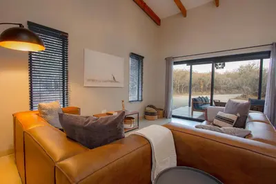 a living room with a couch and a large window at Cheetah's Run in Marloth Park