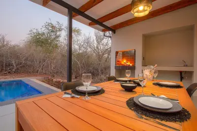 a dining room with a table and a swimming pool at Cheetah's Run in Marloth Park