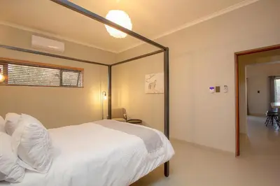 a bedroom with a white bed and a large mirror at Cheetah's Run in Marloth Park