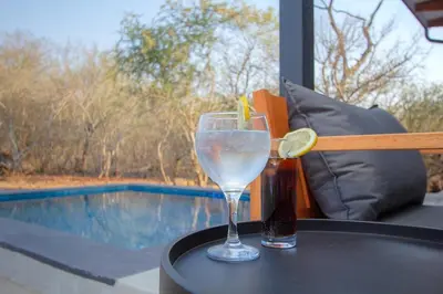 a drink sitting on a table next to a pool at Cheetah's Run in Marloth Park