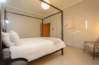 a bedroom with a canopy bed and a chair at Cheetah's Run in Marloth Park