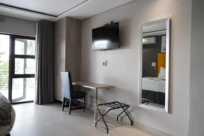 a room with a table and a mirror and a bed at Khayalami Hotel - Mbombela in Nelspruit
