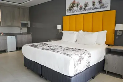 a bedroom with a large bed and a kitchen at Khayalami Hotel - Mbombela in Nelspruit