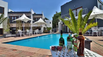a table with wine bottles and glasses next to a swimming pool at Khayalami Hotel - Mbombela in Nelspruit