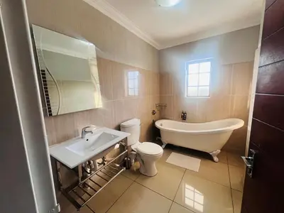 a bathroom with a tub and a toilet and a sink at Khayalami Hotel - Mbombela in Nelspruit