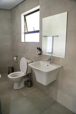 a bathroom with a sink and a toilet and a mirror at Khayalami Hotel - Mbombela in Nelspruit