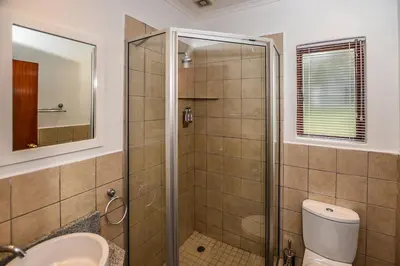 a bathroom with a shower with a toilet and a sink at Penny's Place on Greenway in White River