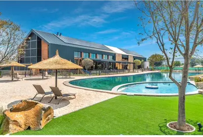 a pool with chairs and umbrellas next to a building at Taina Apartment @ Green Creek in Pretoria