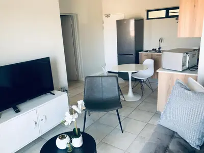 a living room with a couch and a table with a tv at Taina Apartment @ Green Creek in Pretoria