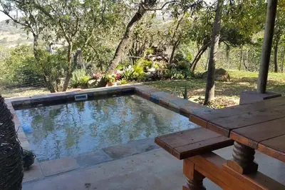 a swimming pool with a wooden table and a bench at InnibosRus Self-catering in White River