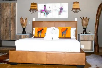 a bedroom with a large bed with orange pillows at Mela Luxury Game Lodge in Pretoria