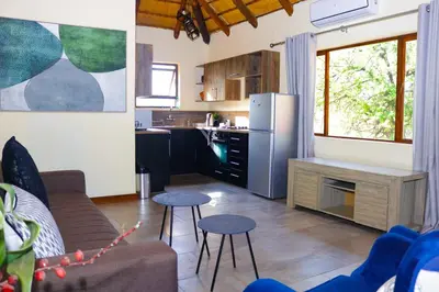 a kitchen and a living room with a couch and chairs at Mela Luxury Game Lodge in Pretoria