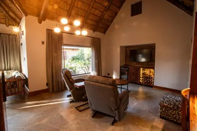 a living room with chairs and a tv and a table at Lapeng Guest Lodge in Burgersfort