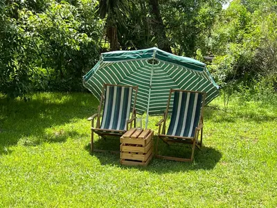 two chairs sitting under an umbrella in the grass at Pan's Breeze Overnight Accommodation in Dalmada AH