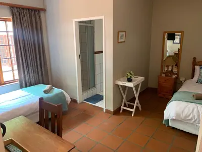 a room with two beds and a table and a mirror at Barnyard Venue in Ermelo