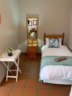 a bedroom with a bed and a table and a mirror at Barnyard Venue in Ermelo