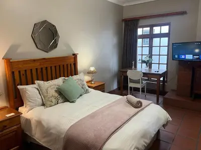 a bedroom with a bed with a desk and a television at Barnyard Venue in Ermelo