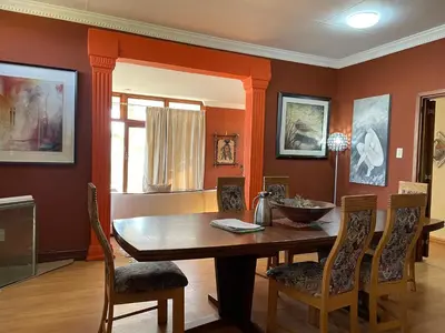 a dining room with a wooden table and chairs at Royal Views in Hartbeespoort