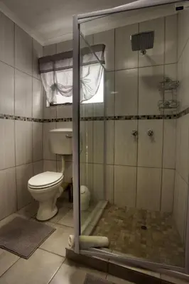 a bathroom with a toilet and a glass shower at Shebamona No loadshedding in Marloth Park