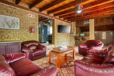 a living room with leather furniture and a tv at Shebamona No loadshedding in Marloth Park
