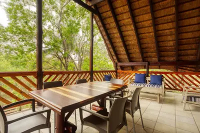 a wooden table and chairs on a screened in porch at Shebamona No loadshedding in Marloth Park