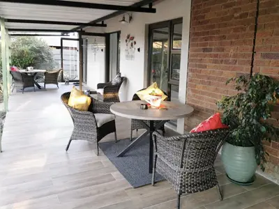 a patio with a table and chairs and a brick wall at 19th on Bloekom Guesthouse in Secunda