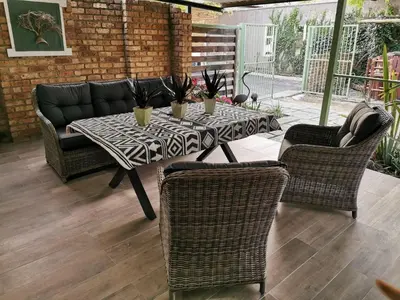 a table with chairs and a couch on a patio at 19th on Bloekom Guesthouse in Secunda